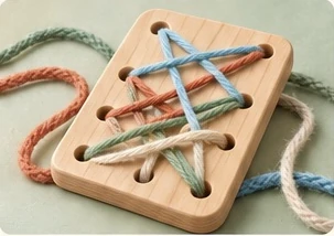 A wooden lacing board threaded with blue, green and coral yarn.